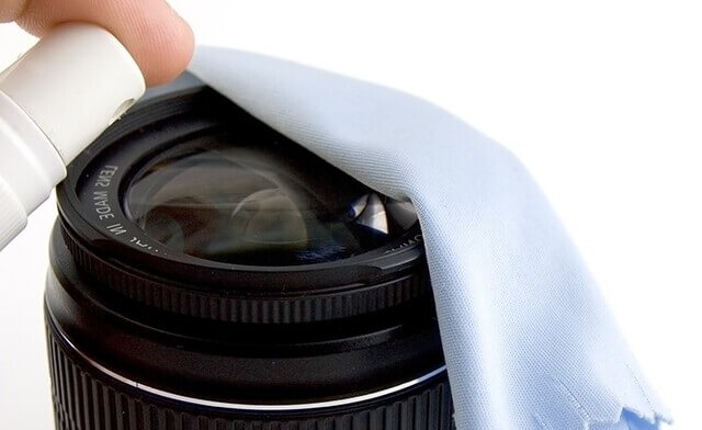 Person cleaning a camera lens with a microfiber cloth